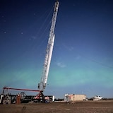 A rocket standing upright in the middle of a plain.