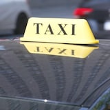 Une enseigne lumineuse de taxi est posée sur le toit d'un véhicule.