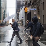Des Torontois circulent au centre-ville, se protégeant du froid et de la pluie.
