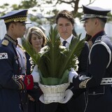 Un homme et deux soldats portant une gerbe de fleurs.