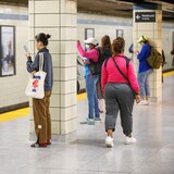 Mga commuter hawak ang kanilang cellphone sa subway.