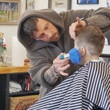 Firsikov finishes off Henry Porter's haircut at Fogtown Barber, a shop on Water Street in downtown St. John's. (Caroline Hillier/CBC)