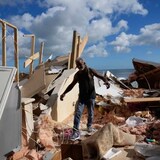 A man walks through the wreckage of the beachfront home that collapsed following beach erosion from Hurricane Nicole on Nov. 12, 2022, in Wilbur-By-The-Sea, Fla. A new UN report has some key points to make before the world hits 1.5 C of warming, a threshold where scientists say 'risks start to pile up.' (Rebecca Blackwell/The Associated Press)
