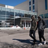 Trois jeunes marchent devant un bâtiment. 