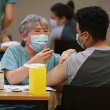 Une professionnelle de la santé injecte un vaccin à un étudiant.