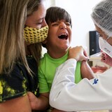 Le jeune Brésilien Leonardo Larussi crie dans les bras de sa mère en recevant une dose du vaccin de Pfizer.