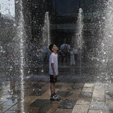 Un garçon se rafraîchit dans une fontaine durant une vague de chaleur à Pékin, en Chine.