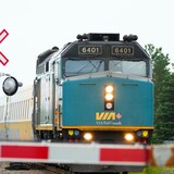 Un train de passagers de VIA Rail traverse un passage à niveau.