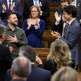 Volodymyr Zelensky, souriant et la main sur le coeur, applaudi par les députés et Justin Trudeau.