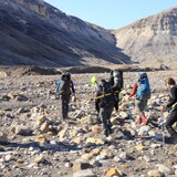 A group of people walk across a rocky terrain. 