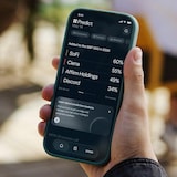 A person looking at the screen of a smartphone in their hand. It displays an app for the prediction market.