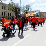 Des personnes vêtues de chandail orange défilent sur le boulevard Memorial à Winnipeg.