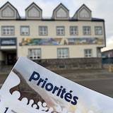 Un document des priorités de la commission scolaire avec en arrière-plan le Centre de la francophonie à Whitehorse.