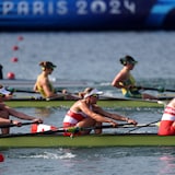 Trois embarcations en pleine course au huit de pointe féminin aux Jeux olympiques de Paris.