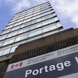 Enseigne du gouvernement fédéral devant un gratte-ciel vu en contre-plongée.