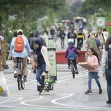 Des passants, dont des enfants, une femme portant le hijab et un homme à vélo, sont dans une rue de Montréal.