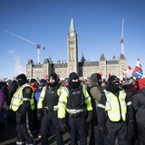 A line of anti-mandate protesters stands face-to-face with a line of police officers in downtown Ottawa on Saturday, Feb. 19, 2022. 