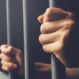 Un détenu tenant les barreaux d'une prison.