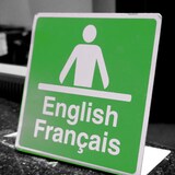 Un cartel que anuncia servicios en  inglés y francés, con el icono de un hombre delante de un escritorio.
