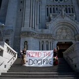 Sarain Fox, right, and Chelsea Brunelle of the Batchewana First Nation unfurled a banner reading 'Rescind the Doctrine' outside the mass presided over by Pope Francis at the National Shrine of Saint Anne de Beaupre in Quebec last summer. (John Locher/The Associated Press)
