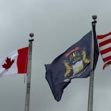 Les drapeaux canadiens et américains flottent à côté du drapeau de la ville de Port Huron.