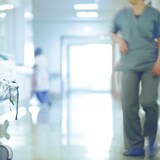 Une infirmière marche d'un pas pressé dans un corridor d'hôpital.  