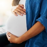 Une femme enceinte tient son ventre.
