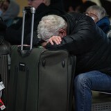 رجل وضع رأسه على حقيبة سفره في مطار فانكوفر الدولي.