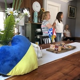 Un coussin aux couleurs du drapeau ukrainien est à l'avant-plan, on distingue aussi autour de collations un drapeau du québec et du canada. Trois personnes sont en arrière plan. 