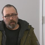 Un homme avec un manteau d'hiver, des lunettes et une barbe.
