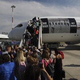 مواطنون أوكرانيون فروا من الحرب في بلادهم يستقلون طائرة في مطار فريديريك شوبان الدولي في العاصمة البولندية وارسو من أجل السفر إلى كندا في 4 تموز (يوليو) 2022.