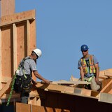Quatre travailleurs de la construction travaillent sur un toit en été.