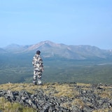 Un homme au sommet d'une montagne regarde l'horizon.