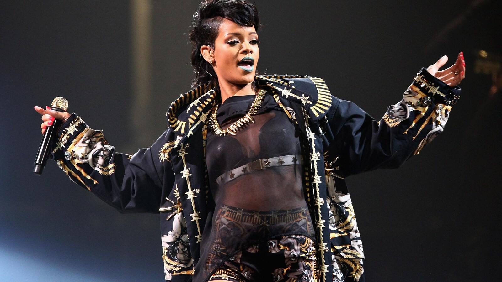 La chanteuse Rihanna est sur scène et écarte les bras.