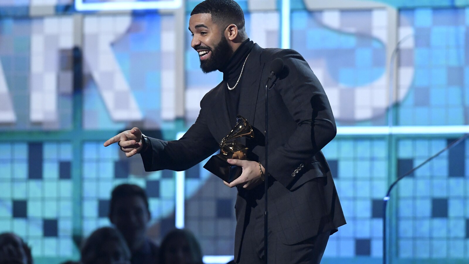 Drake tient un trophée en forme de gramophone dans ses mains.