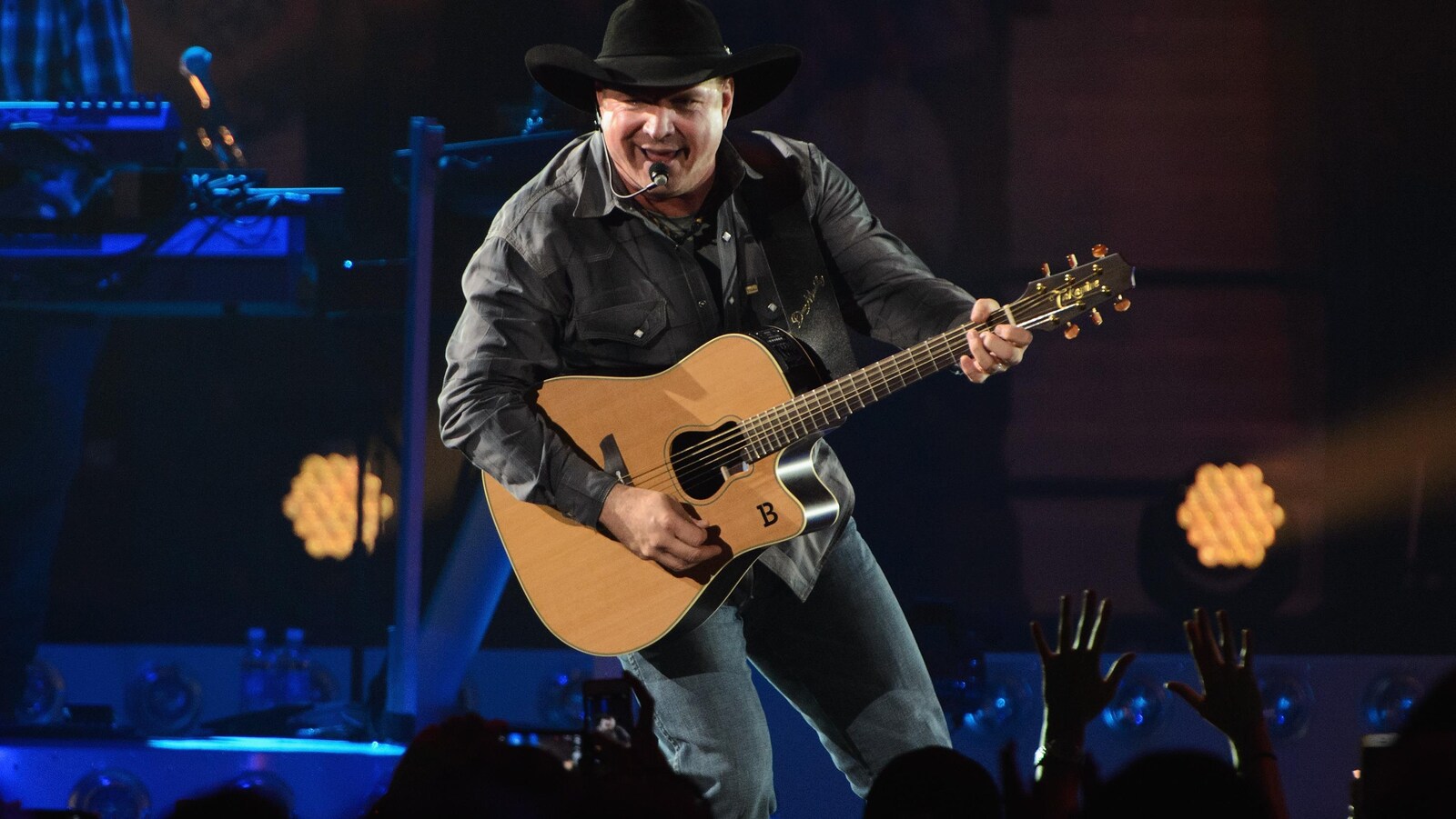 Garth Brooks, sur scène, chante avec une guitare à la main pendant un spectacle.