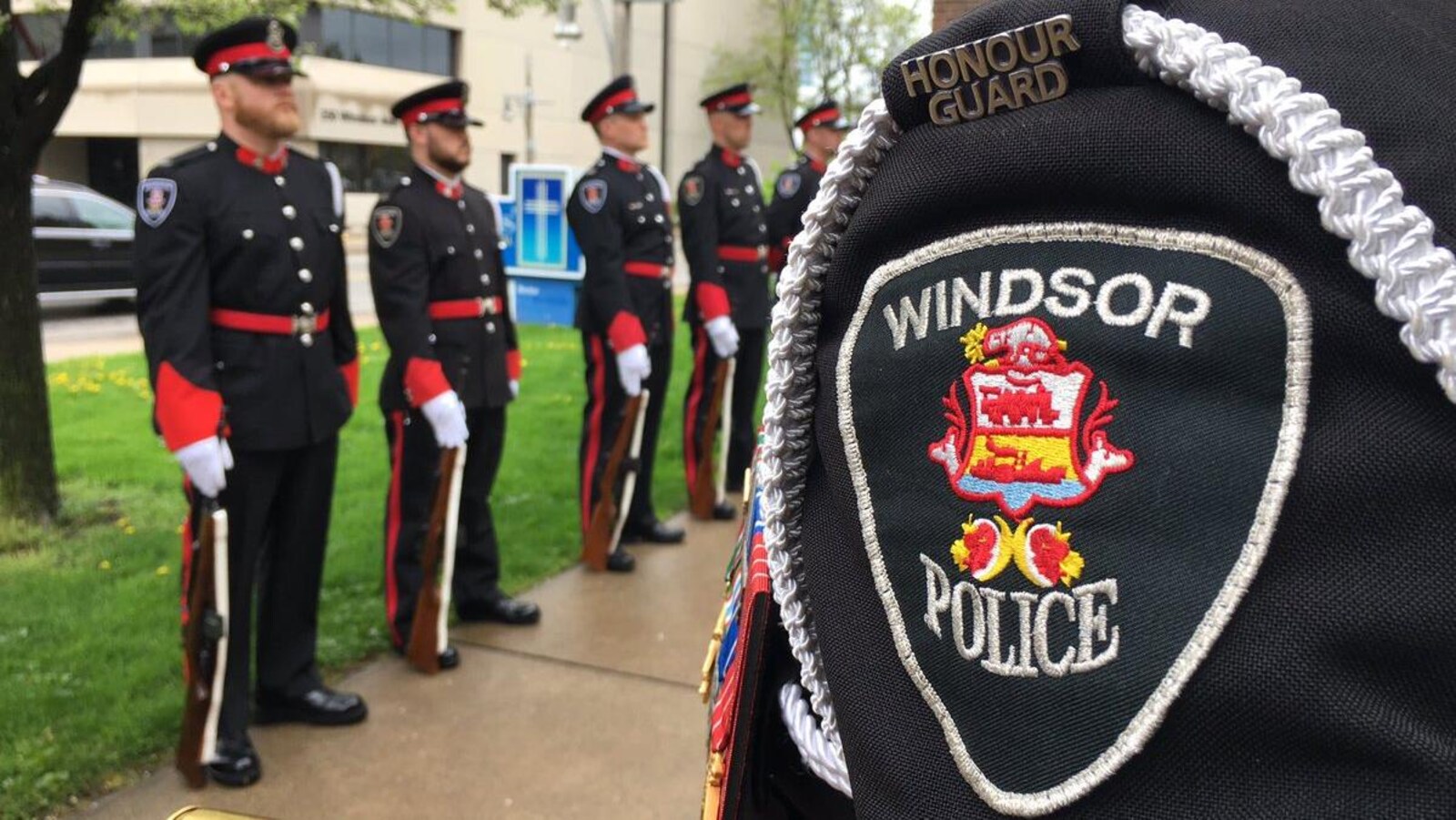 Des policiers en uniforme d'apparat lors d'une cérémonie. Au premier plan, l'épaule d'un agent montre l'écusson de la police de Windsor.