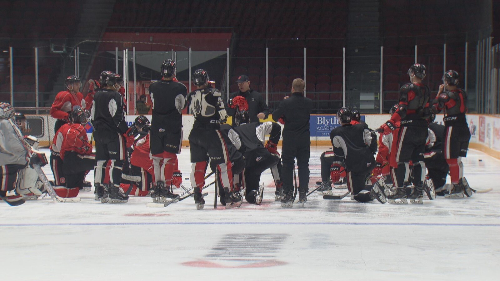 Un groupe de joueurs de hockey écoutent un entraîneur