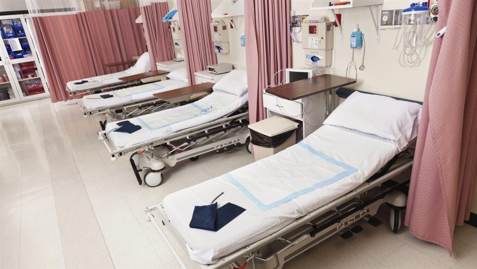 Photo de 4 lits séparés par des rideaux à l'urgence.