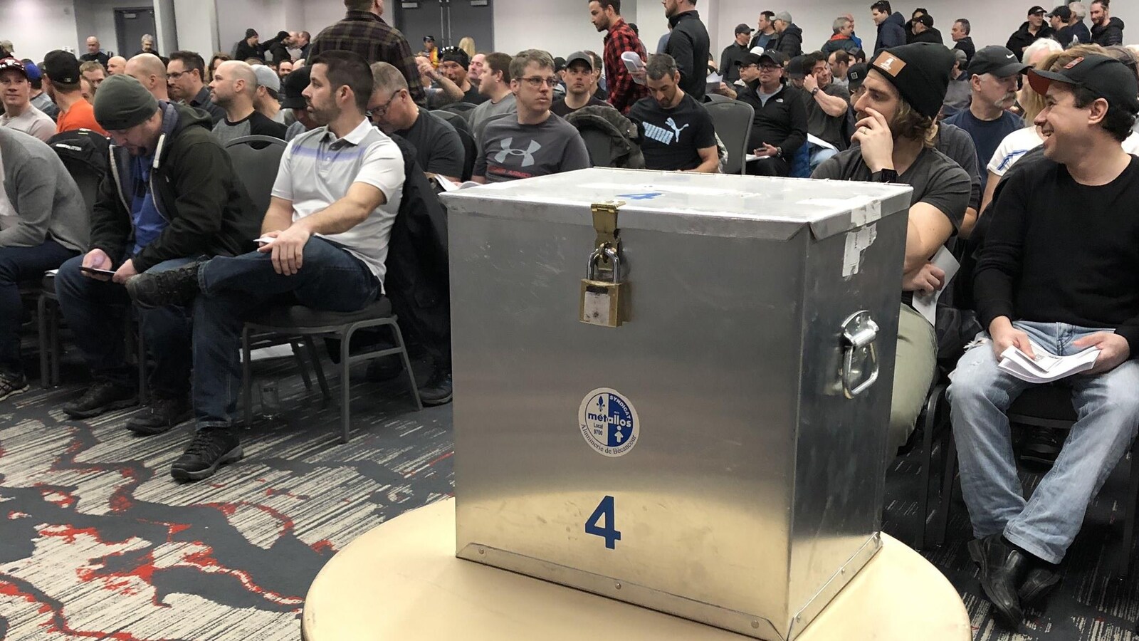 Boîte de votes de l'ABI devant des syndiqués dans une salle.