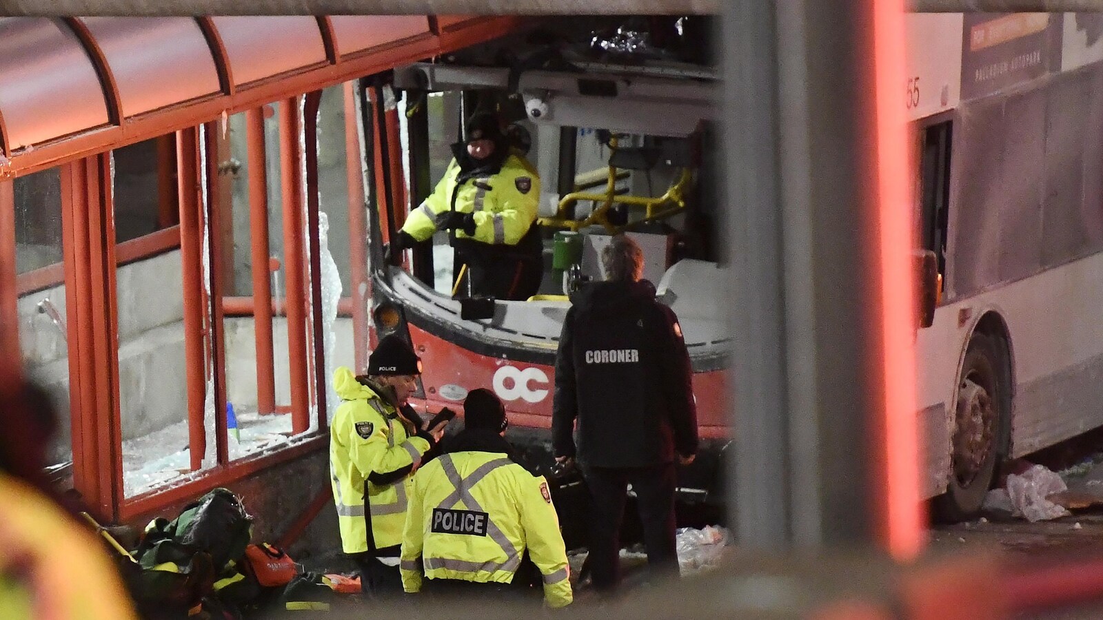Des policiers en habits d'hiver devant un autobus accidenté.