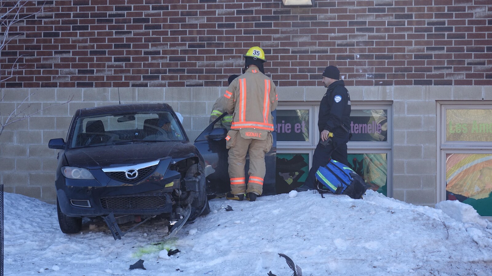 Une voiture accidentée de couleur noire est immobile devant la garderie Les Amours du Roitelet.