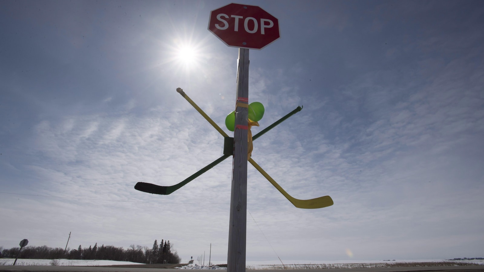 Une paire de hockey est attachée à un panneau d'arrêt en hommage aux Broncos de Humboldt.
