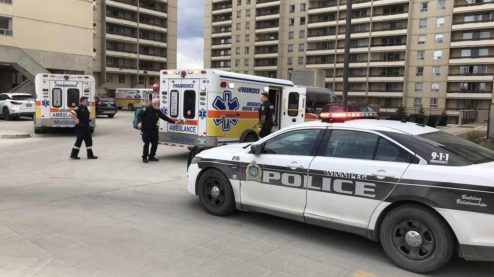 Des auto-patrouilles et des ambulances à l'extérieur d'un immeuble résidentiel.