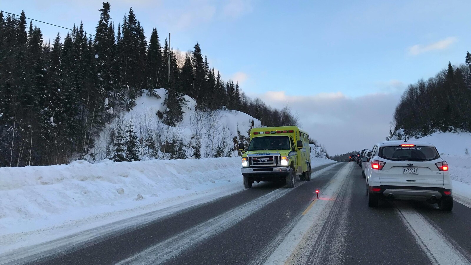 Une ambulance quitte les lieux d'un accident pendant que des voitures font la file en sens inverse.