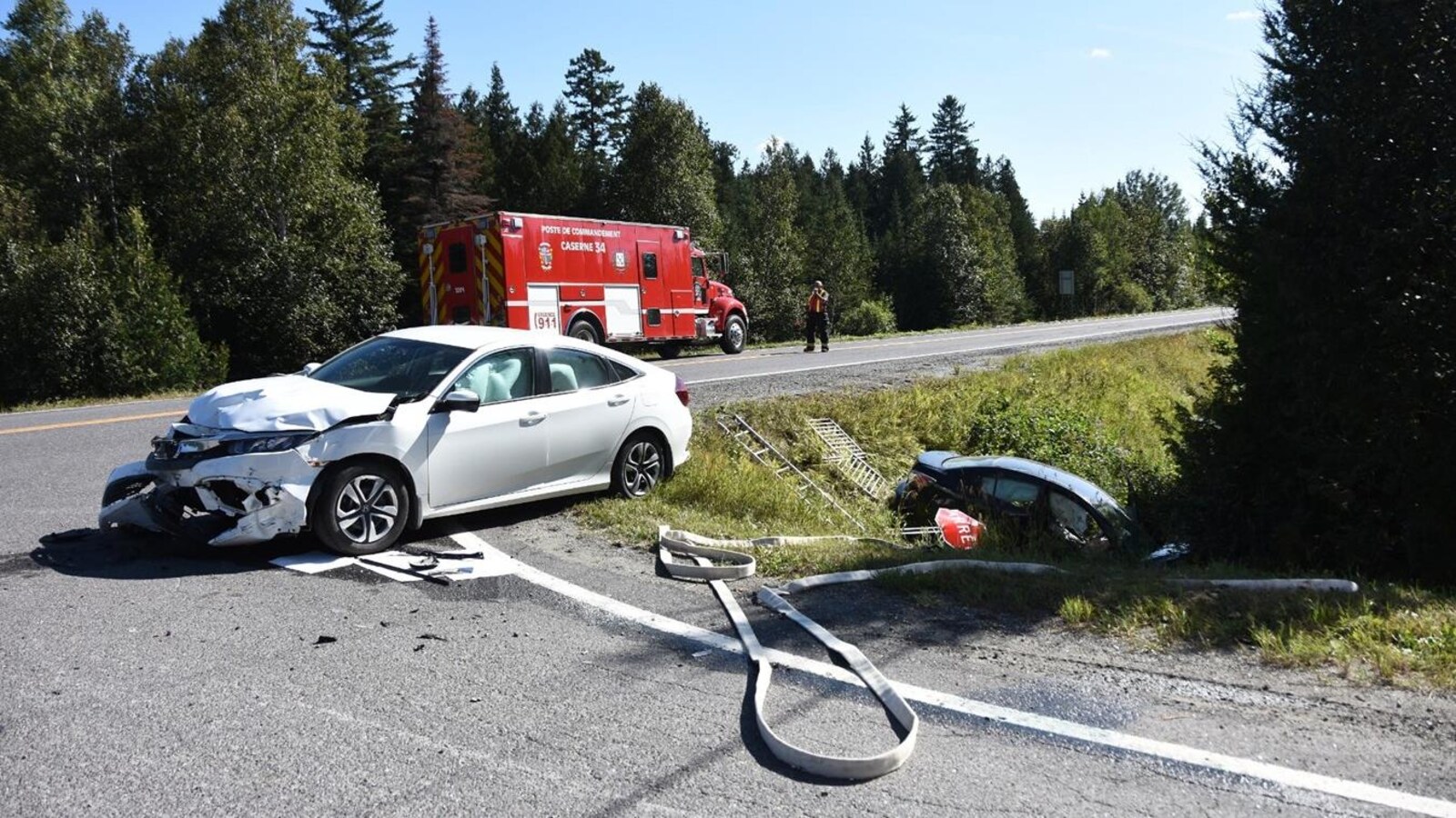 Le pare-chocs avant d'un milieu est abouti. On voit une voiture à l'arrière tombée dans un fossé en bordure de route.