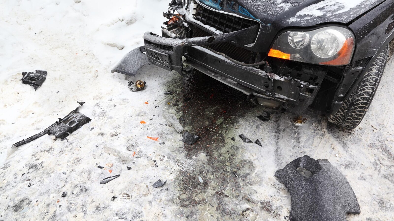 Une voiture noire accidentée sur une route enneigée