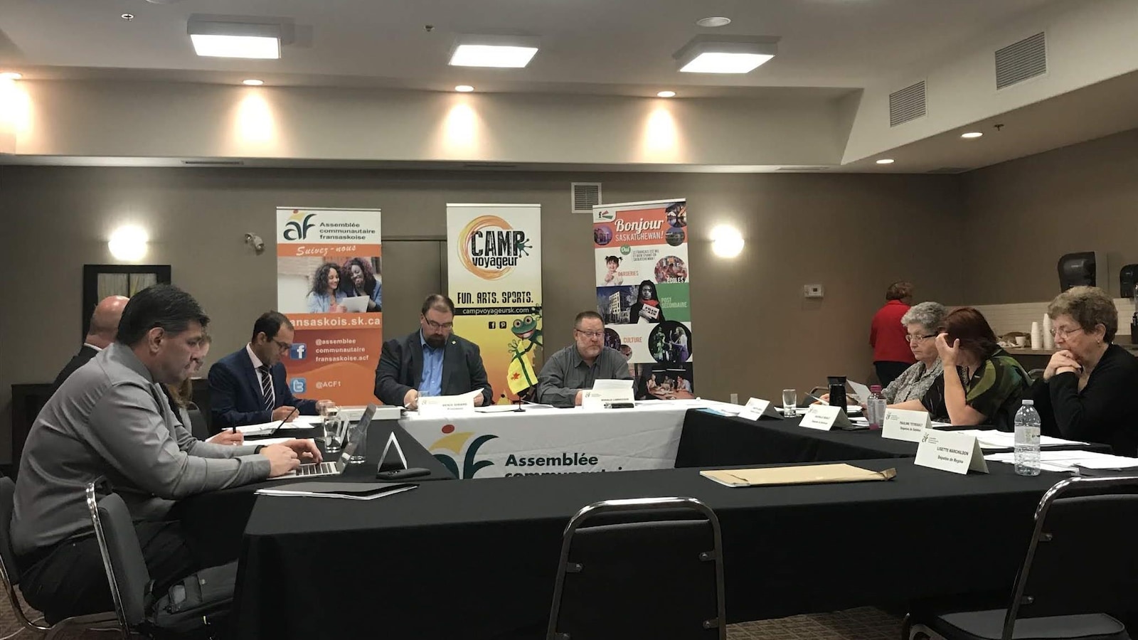 Une salle de réunion avec des hommes et des femmes installés autour d'une table.