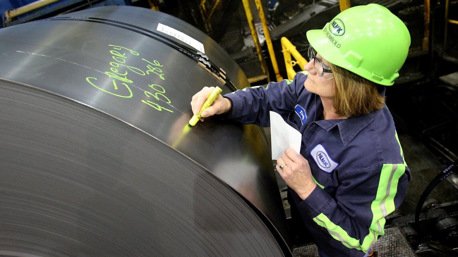 Une ouvrière marque une bobine d’acier.