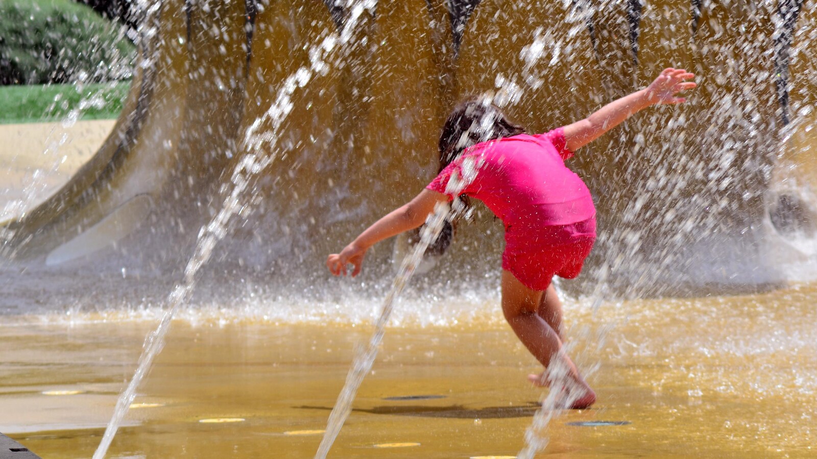 Une fillette de 4 ans s'amuse dans une fontaine.